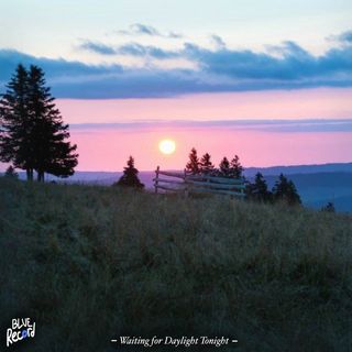 A photograph of the sun either rising or setting over a hill in the countryside