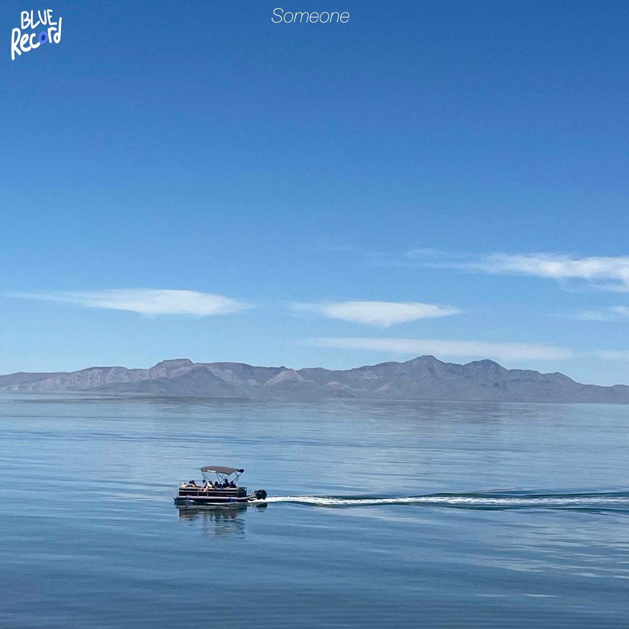 A lone boat sitting in the middle of a large lake, with mountains in the background